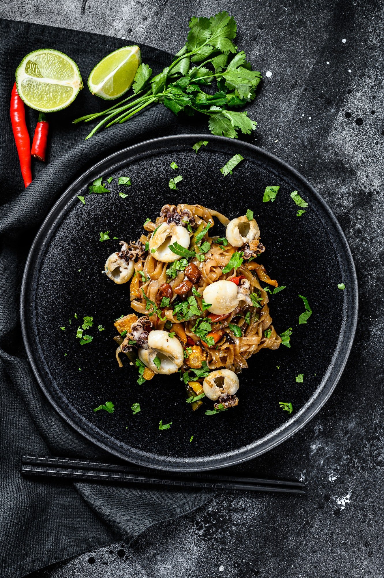 homemade-stir-fry-damage-noodles-with-seafood-and-vegetables-in-a-plate-black-background-top-view.jpg
